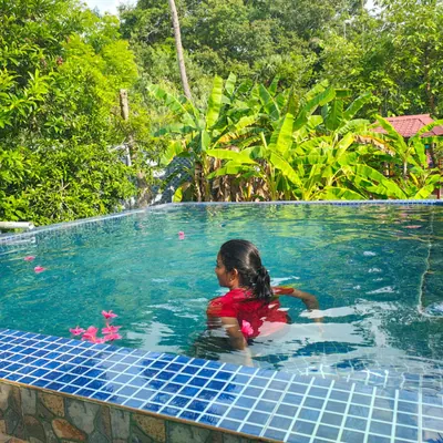 Guest swimming in the pool surrounded by greenery at Re Leaf Resort