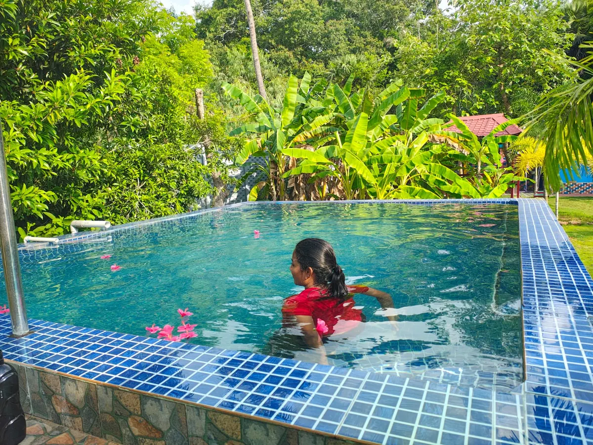 Guest in the swimming pool surrounded by tropical garden at Re Leaf Resort